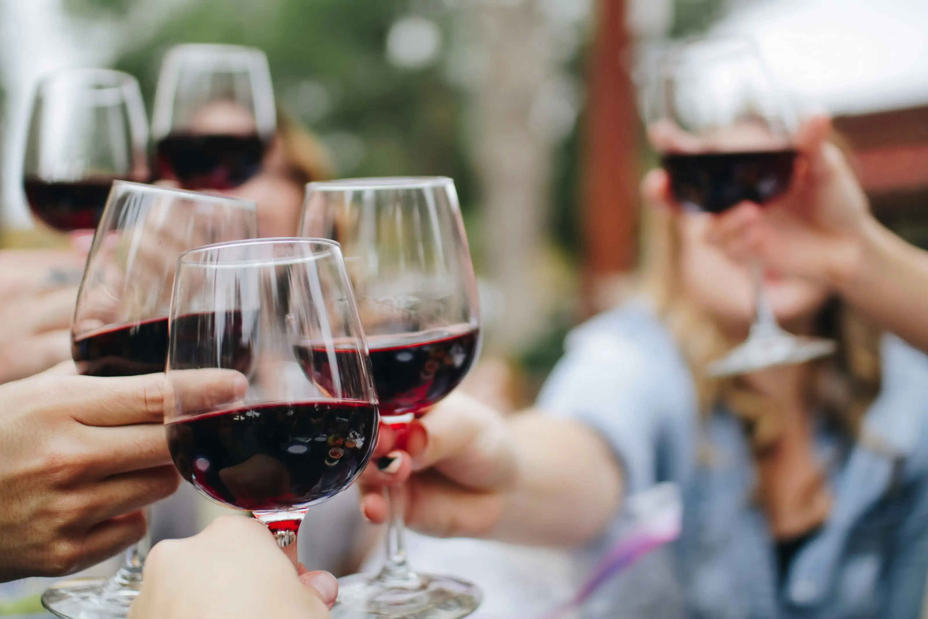 Mehrere Gläser Rotwein stoßen über einem gedeckten Tisch an