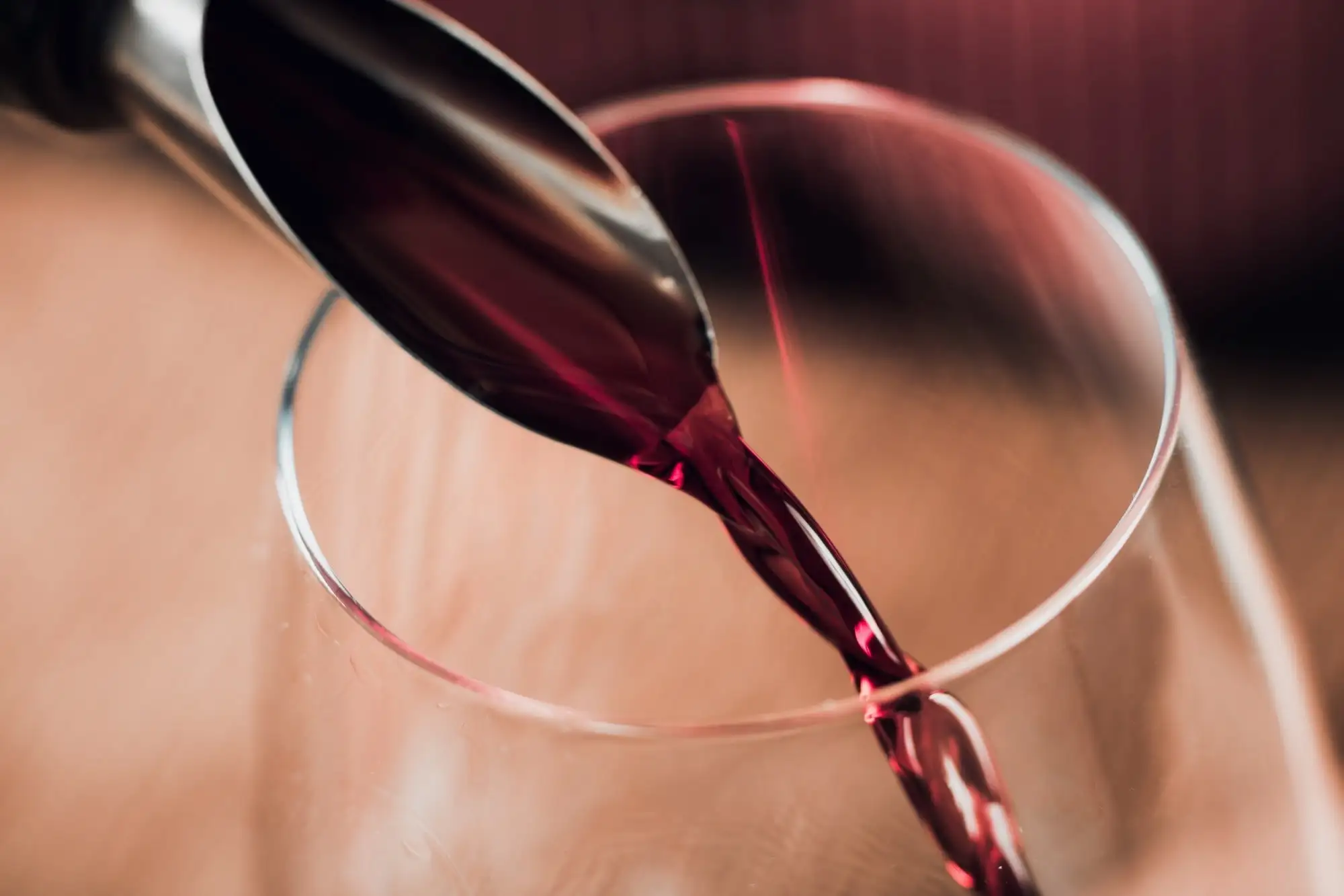Rotwein wird in ein Glas eingeschenkt